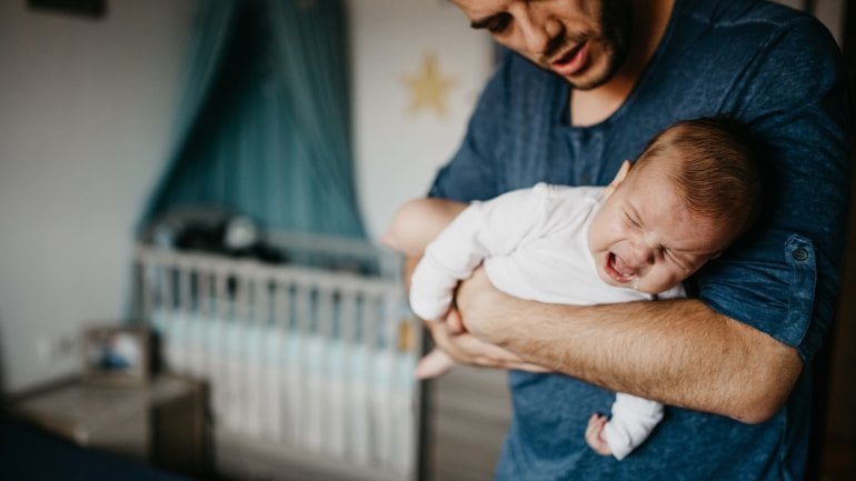 Vater hält Baby mit Rotavirus-Infektion auf dem Arm.