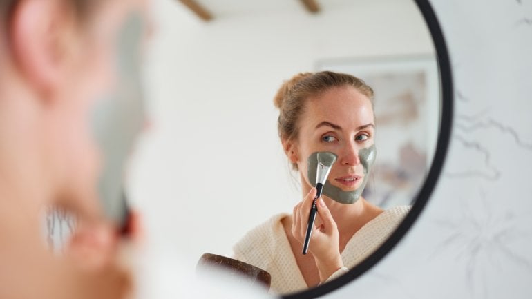 Eine Frau behandelt ihr Gesicht mit einer Heilerde-Maske.