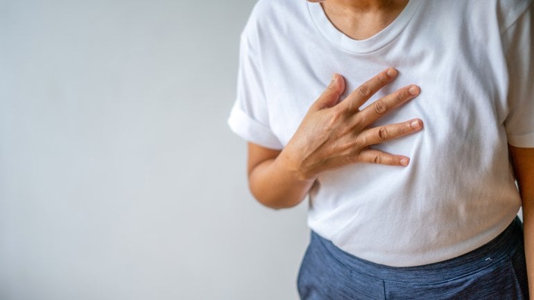 Frau fasst sich an die Brust und leidet an pulmonaler Hypertonie.