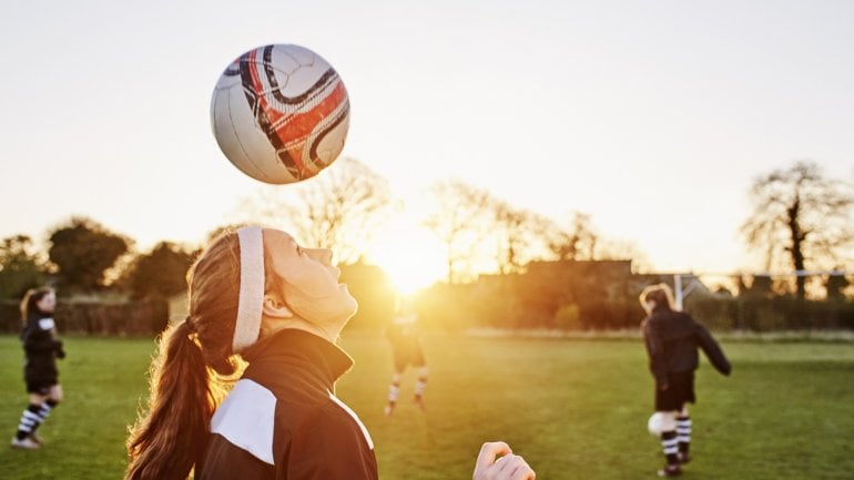 Frau macht Kopfball auf dem Fußballplatz