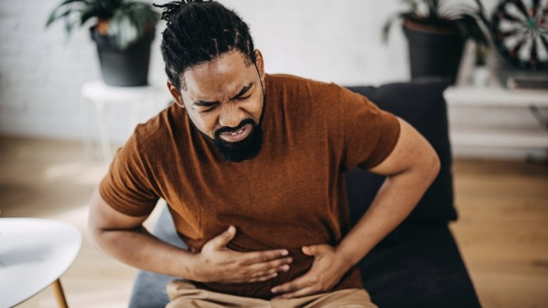 Mann mit Splenomegalie fasst sich an schmerzenden Bauch.