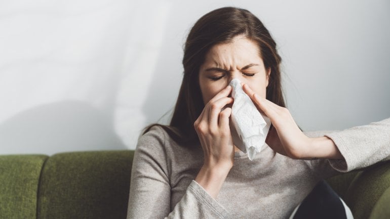 Frau mit Granulomatose mit Polyangiitis putzt sich die Nase.