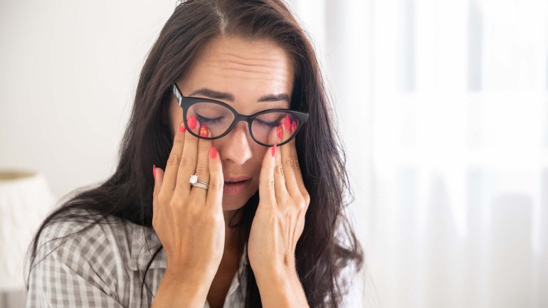 Eine Frau reibt sich die schmerzenden Augen