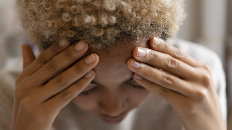 Eine junge Frau fasst sich an den schmerzenden Kopf