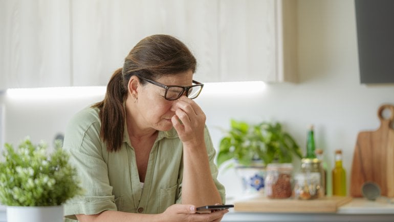 Frau mit Mouches volantes leidet unter Symptomen der Glaskörpertrübung und kneift Augen zusammen.