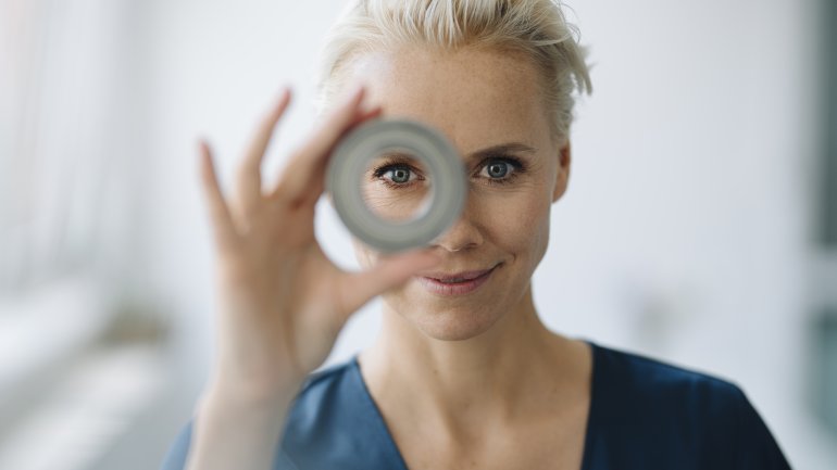 Eine Frau blickt durch ein Objekt.