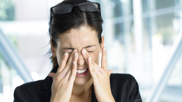 Eine Frau hält sich die Hände an die schmerzenden Augen.