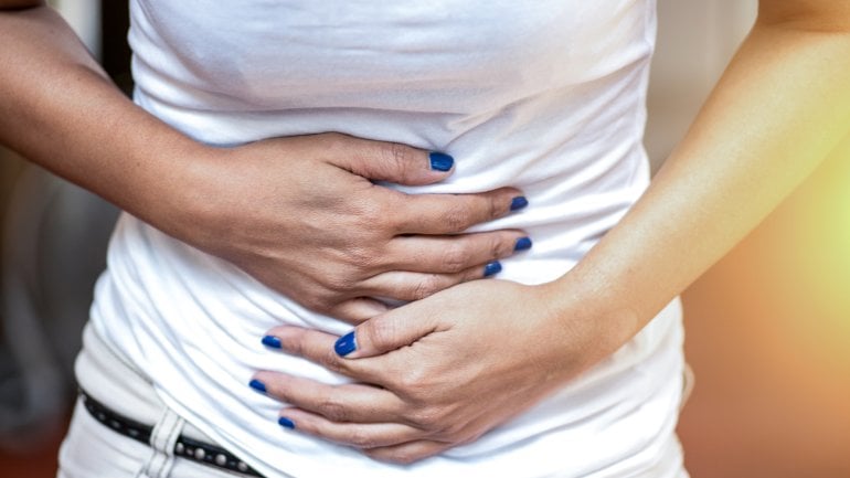 Eine Frau hält sich den Bauch wegen Bauchkrämpfen