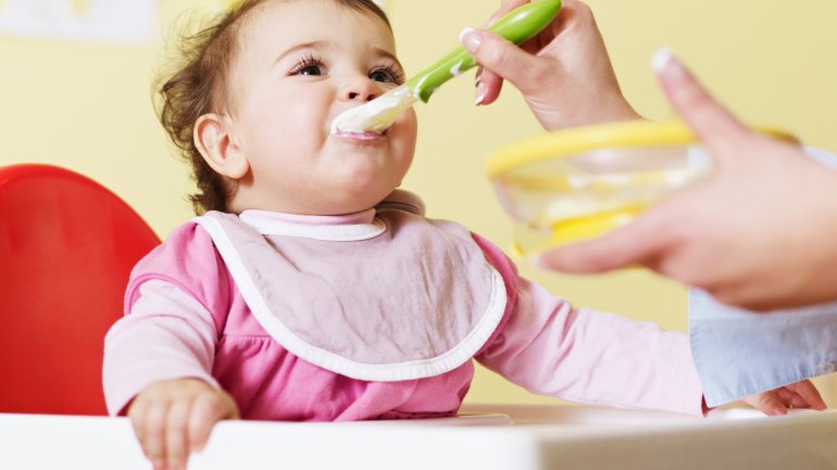 Das Bild zeigt ein Baby, das gefüttert wird.