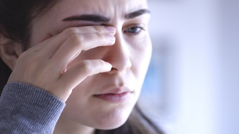 Eine Frau reibt sich das schmerzende Auge