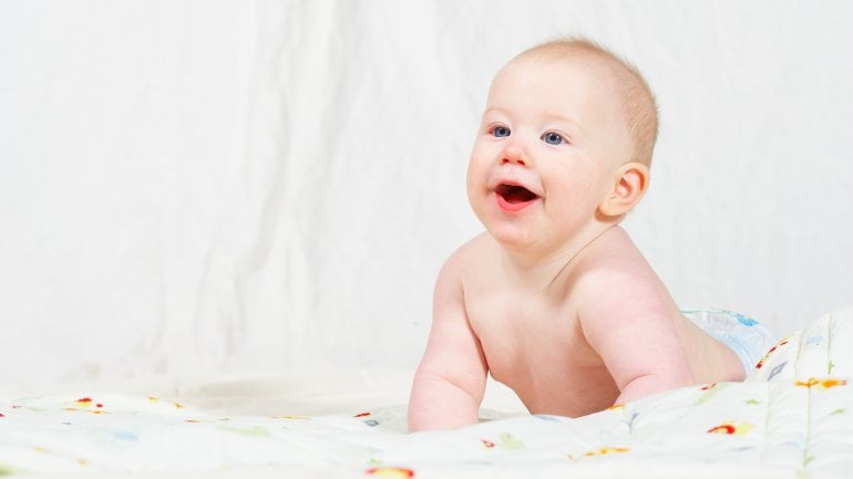 Das Bild zeigt ein Baby in einem Fotostudio, das auf dem Boden liegt.