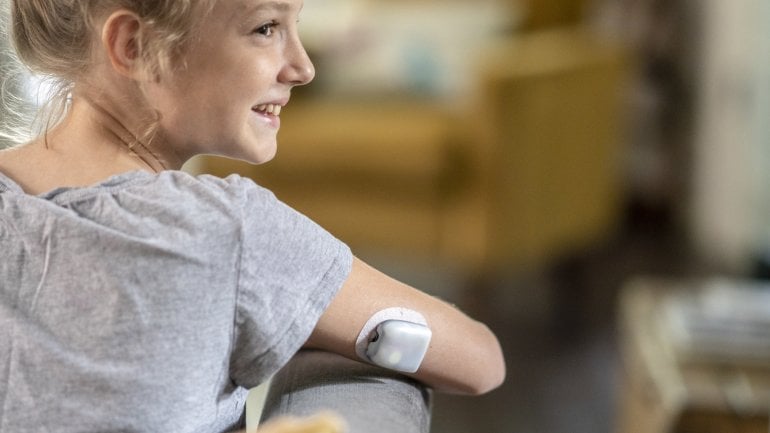 Ein junges Mädchen trägt einen Langzeitsensor zur Zuckermessung bei Diabetes Typ 1