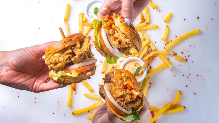 Drei unterschiedliche Burger im Fokus, Pommes im Hintergrund