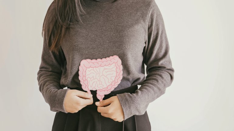 Frau hält sich ein schematisches Bild vom Darm vor den Bauch