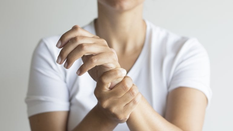 Frau Hält sich das Handgelenk, weil sie Schmerzen hat