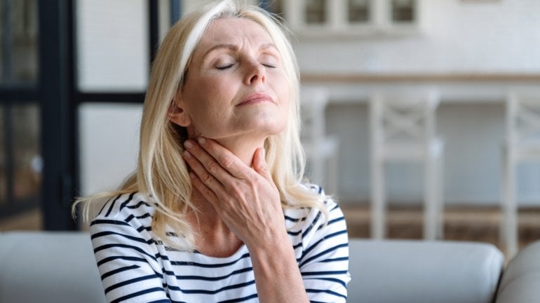 Frau mit geschwollenen Lymphknoten fasst sich an den Hals.