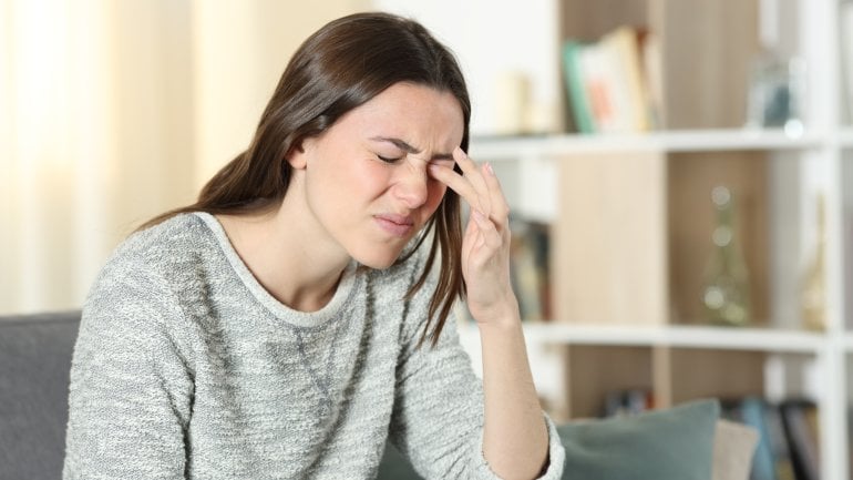 Frau mit Skotom fasst sich ans Auge, weil sie Sehstörungen hat.