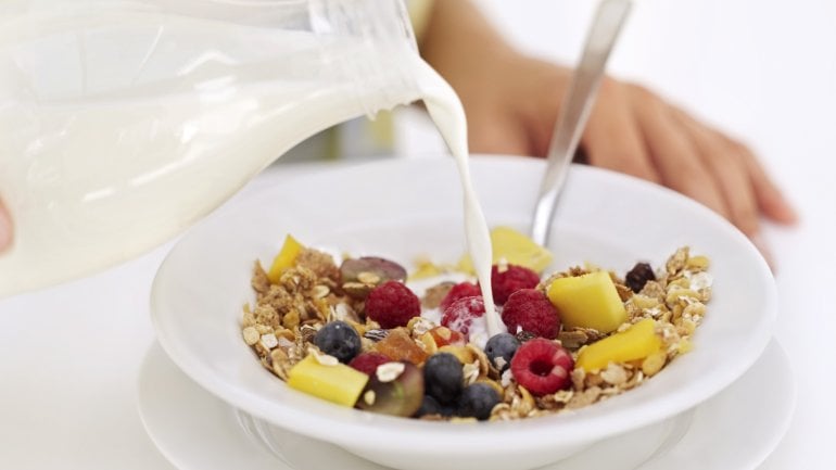 Das Bild zeigt einen Teller mit Müsli in den Milch gegossen wird.