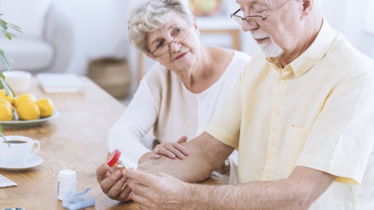 Ein älterer Mann betrachtet eine Tabletten-Dose.