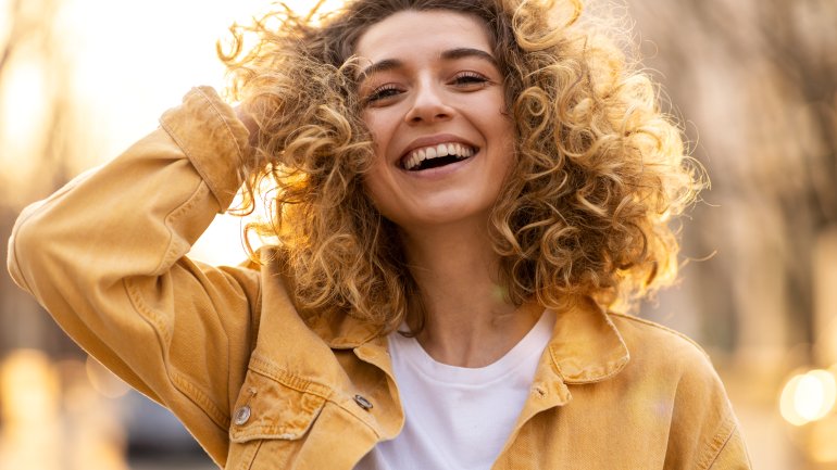 Eine Frau lacht und greift sich in die Haare