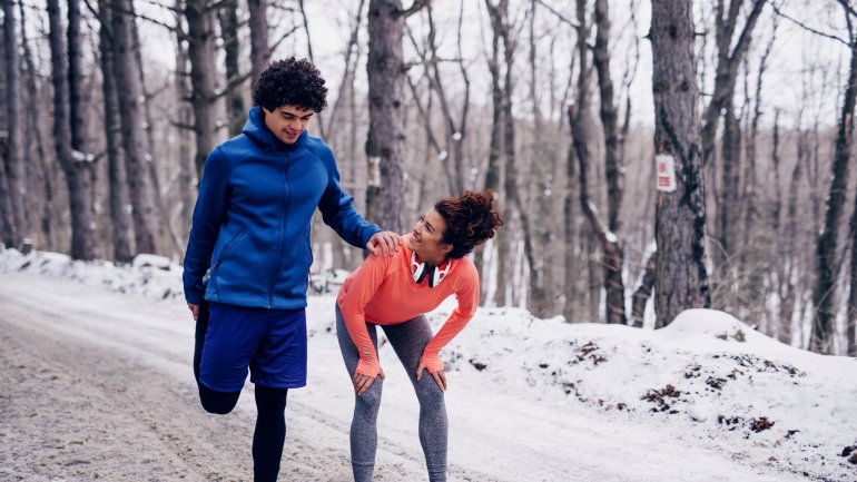 Zwei Jogger machen Dehnübungen.