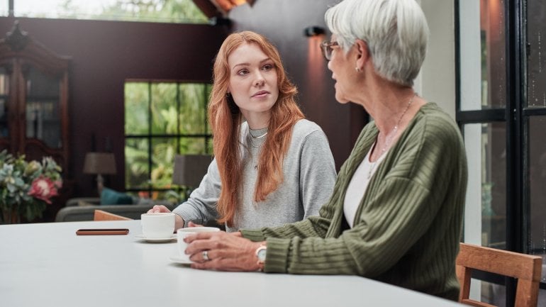 Mutter und Tochter sitzen im Wohnzimmer und unterhalten sich über