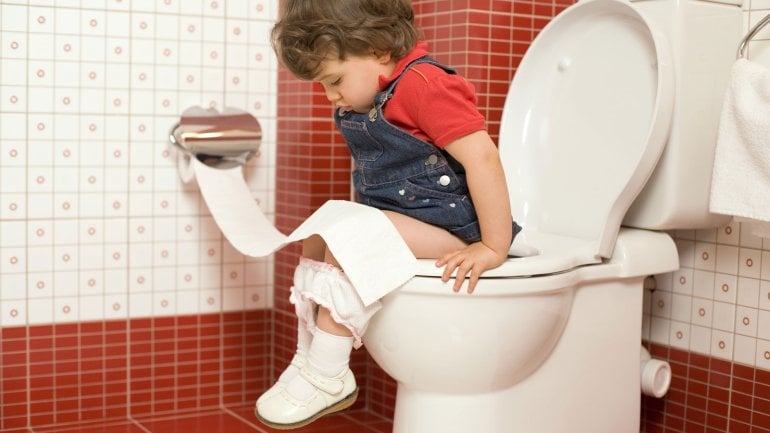 Ein kleines Mädchen sitzt auf dem WC.