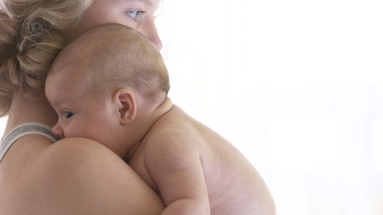 Das Bild zeigt eine Mutter mit ihrem Baby auf dem Arm. 