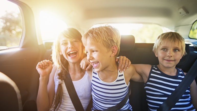 Drei Kinder sitzen angeschnallt im Auto