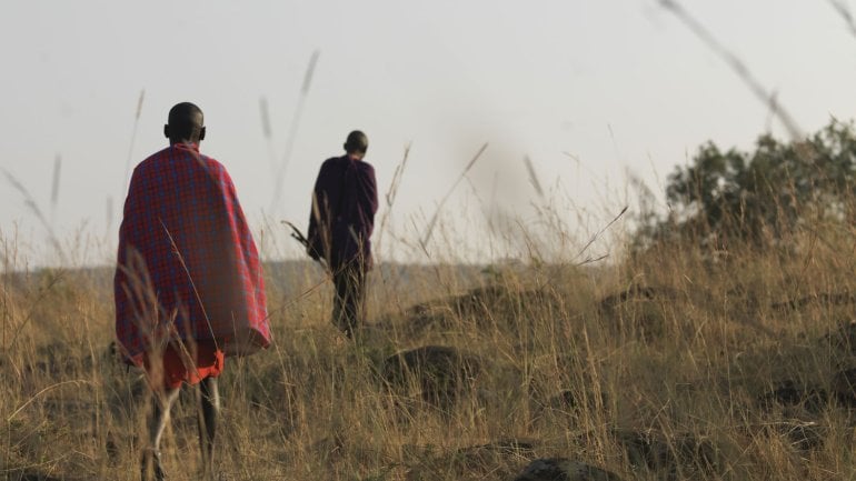 Man sieht zwei Mitglieder von einem afrikanischen Stamm in der Steppe.