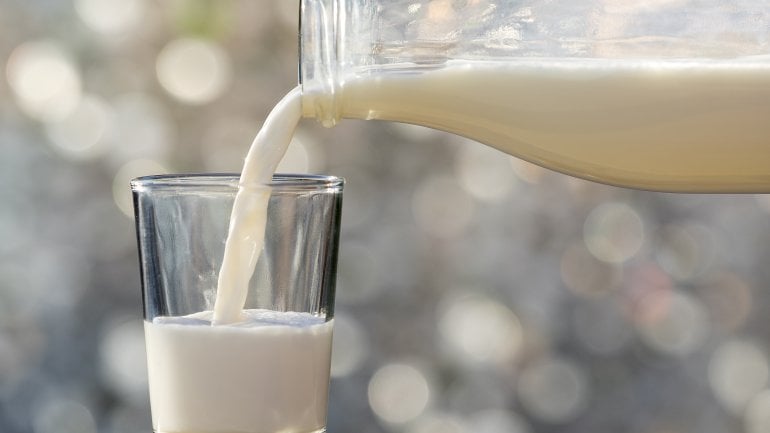 Jemand gießt Milch in ein Glas.