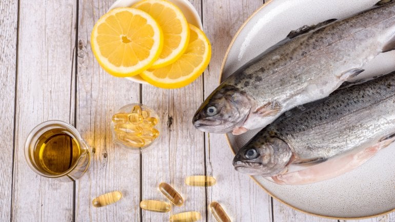 Das Bild zeigt Lebertran-Tabletten, Fisch und Zitrone.