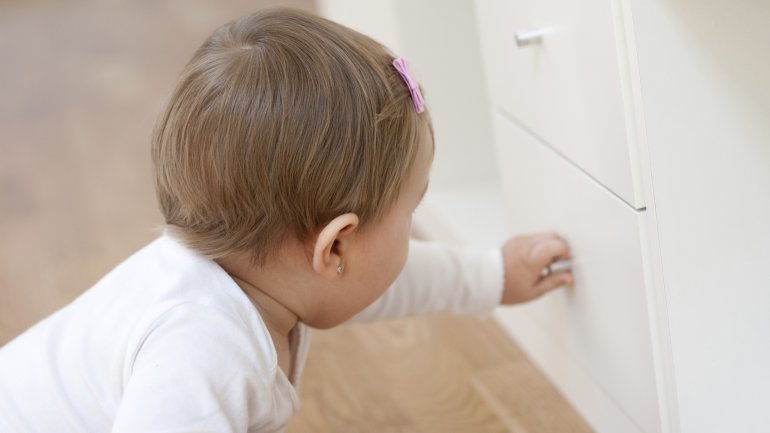 Baby zieht eine Schublade auf.