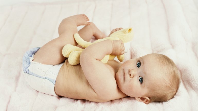 Das Bild zeigt ein Baby auf einem Bett liegend.