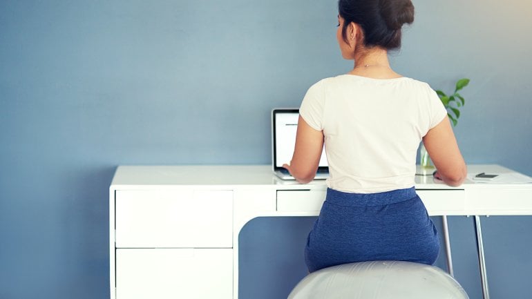 Eine Frau sitzt gerade auf einem Sitzball und ist von hinten zu sehen