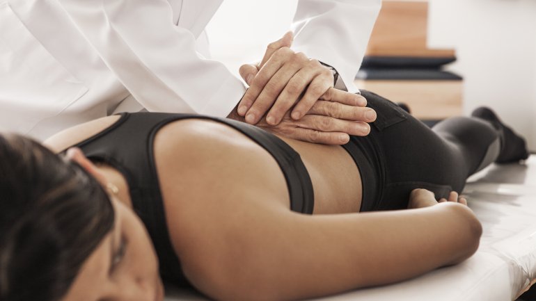 Ein Osteopath behandelt eine junge Frau