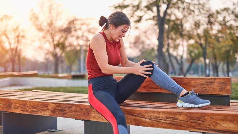 Eine Sportlerin hält sich das Knie