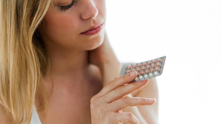 Frau mit Pillenpackung in der Hand.