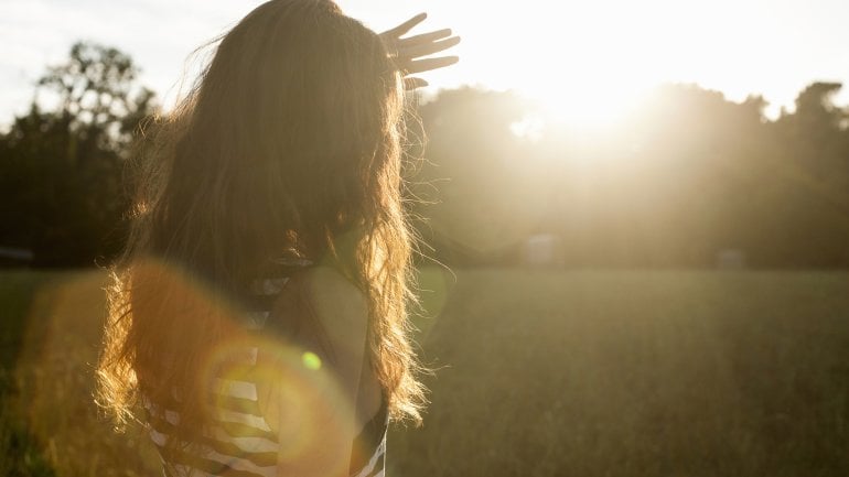 Eine Frau hält schützend ihre Hand vor sich, da die Sonne scheint