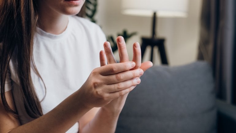 Eine Frau fasst sich an die schmerzenden Finger