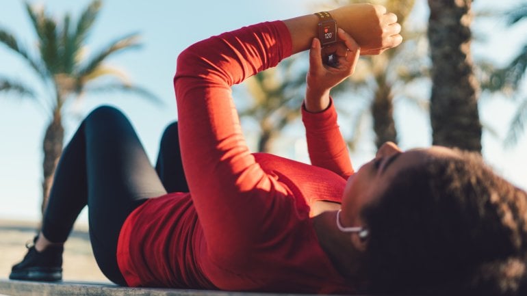 Joggerin misst, auf Bank liegend, den Puls