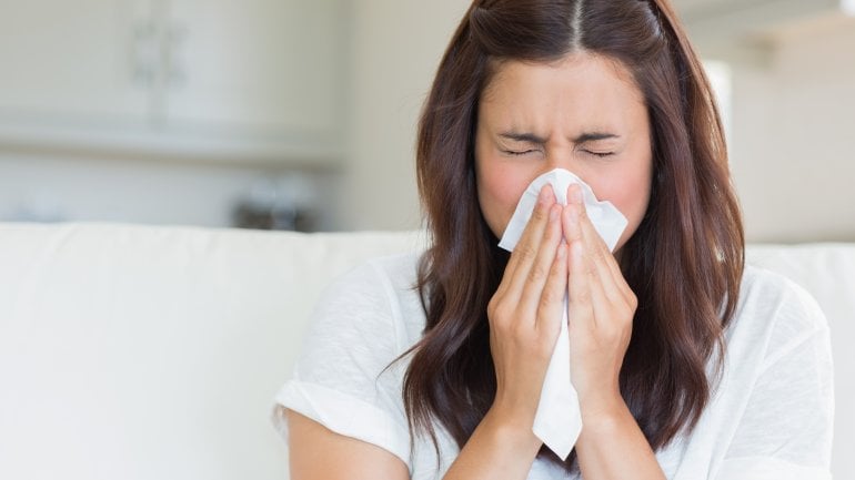 Frau mit Schimmelpilzallergie putzt sich die Nase