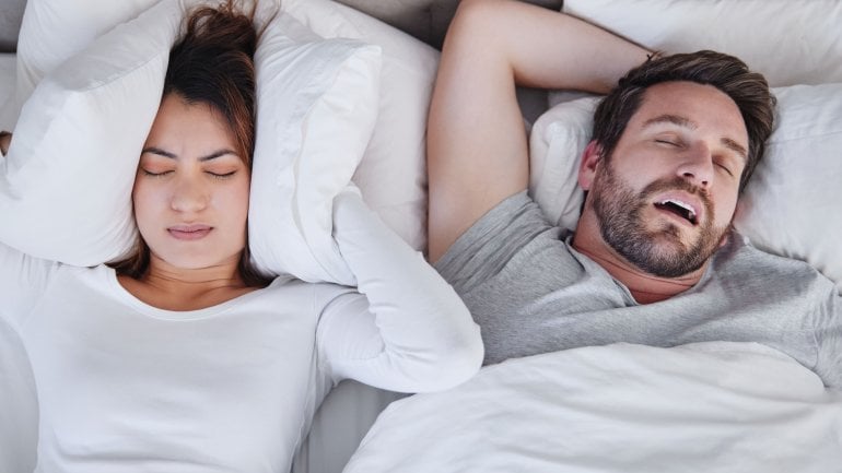 Frau kann nicht schlafen, da Mann mit Schlafapnoe laut schnarcht.