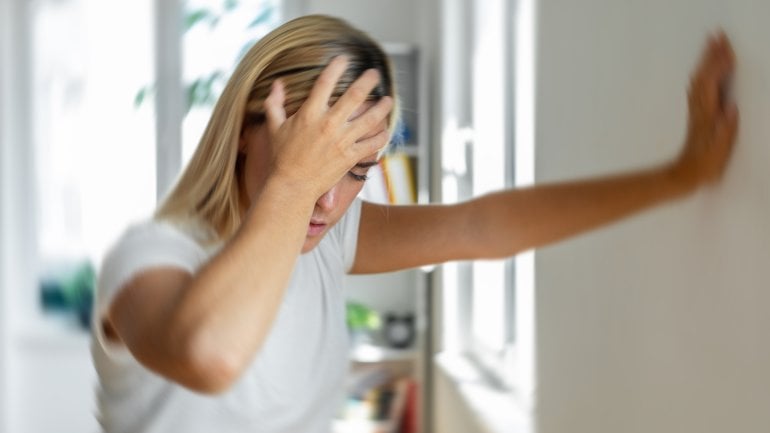 Junge Frau, der nach dem Aufstehen schwindelig ist.