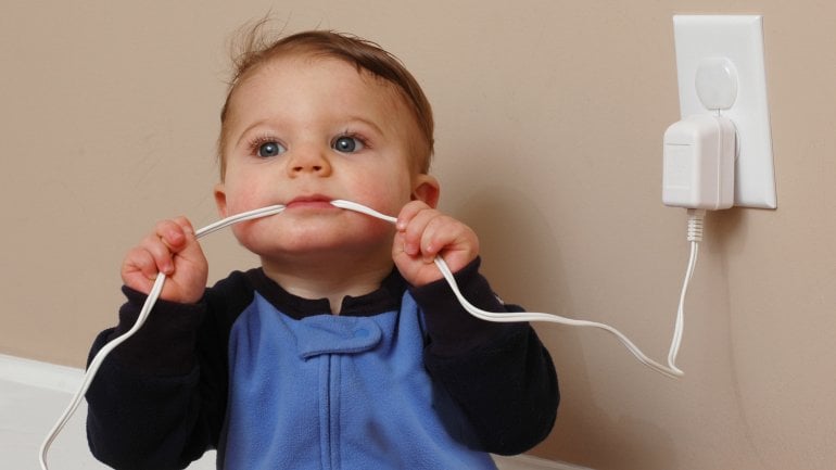 Ein Baby kaut auf einem Stromkabel.