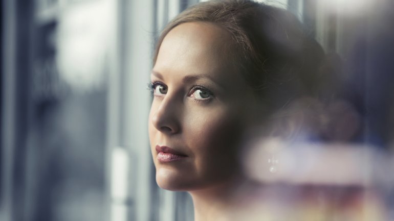 Eine Frau schaut nachdenklich aus dem Fenster.