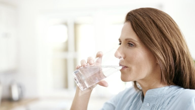 Eine Frau trinkt ein Glas Wasser.