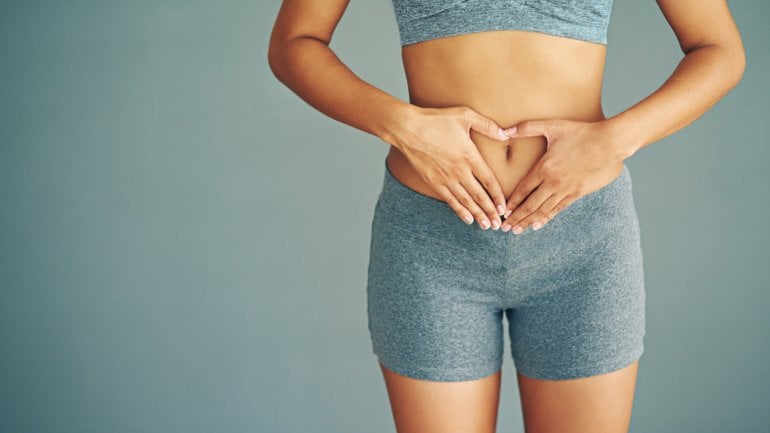 Eine Frau hat die Hände auf ihren Bauch gelegt.