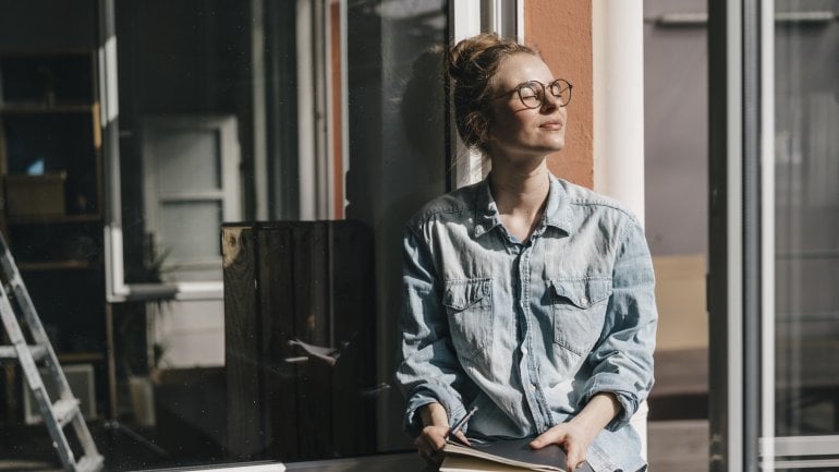 Frau sitzt im Zimmer und sonnt sich, um die Produktion von Vitamin D anzukurbeln.