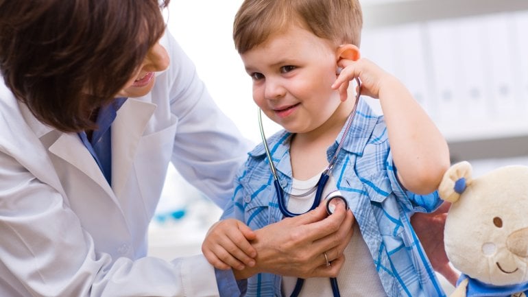 Eine Kinderärztin hört einen kleinen Jungen ab.